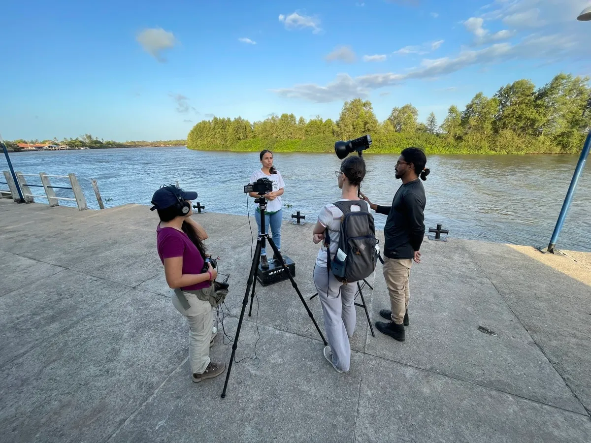 Equipe da Barong gravando às margens de um rio, com tripés e câmeras